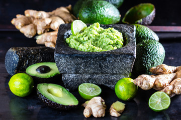 Latinamerican mexican guacamole with avocado ginger, lime in stone mortar