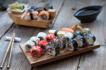 A variety of sushi and green tea set on rustic wooden table.