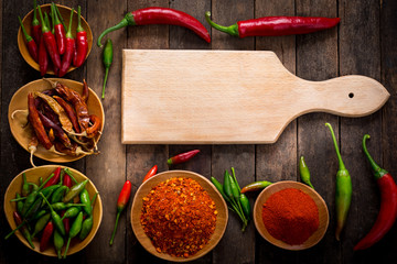 Chili peppers and cutting board on the wooden background