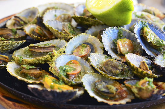 Tasty seafood grilled limpets served with lemon.Lapas grelhadas.Madeira's traditional dish and a typical snack on Canary Islands.Selective focus.

