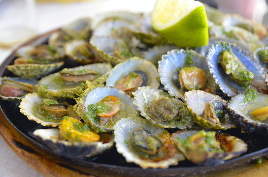 Tasty seafood grilled limpets served with lemon.Lapas grelhadas.Madeira's traditional dish and a typical snack on Canary Islands.Selective focus.
