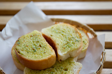 Garlic grilled bread in wooden basket close up.