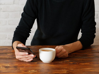 Woman with new smartphone is drinking tea