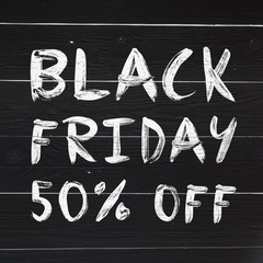 Black friday 50% off brush hand lettering on white painted rustic barn wooden planks. Sale banner. © mykolastock