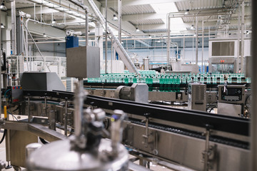 Industrial factory indoors and machinery. Robotic factory line for processing and bottling of pure spring water into canisters and bottles. Selective focus. Short depth of field.