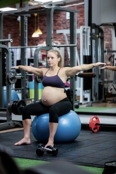 Pregnant woman preforming stretching exercise on fitness ball
