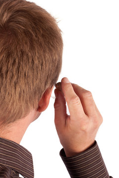 Deaf man's head and hand putting on his behind-the-ear hearing a