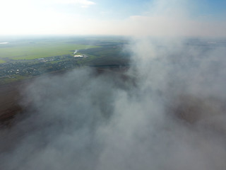 The smoke over the village. Clubs of smoke over the village houses and fields. Aerophotographing areas