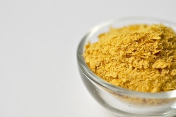 Nutritional yeast close-up on white background with copy space