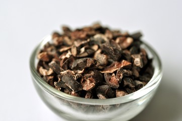 Raw cocoa bean nibs (Theobroma cacao) in bowl on isolated white
