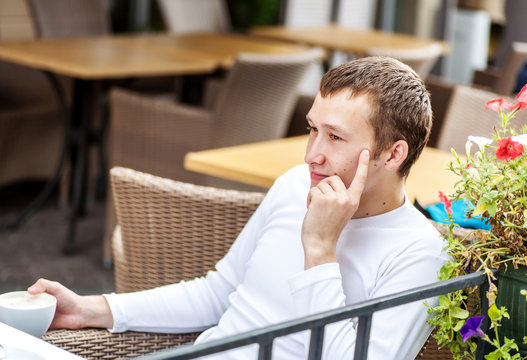 One man drinking coffee at city cafe table outdoors