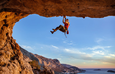 Male climber gripping on handhold while climbing in cave. Rock climbing without rope.