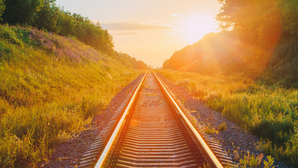 Obraz premium Railway Going Straight Ahead Through Summer Hilly Meadow To Sunset