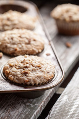 Walnut crumb sweet potato muffins in an old tin on a weathered barn wood table