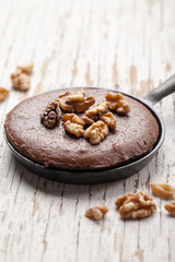 Chocolate brownie topped with walnuts in a cast iron skillet close shot