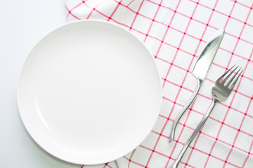 empty white plate and fork knife on red checked tablecloth