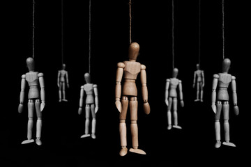 Group of wooden marionettes puppet hangman by rope, on black background