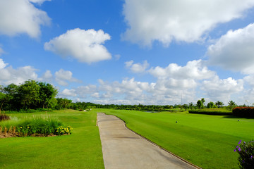 Fototapeta na wymiar landscape view of concrete footpath with blue sky and white clouds background in golf course