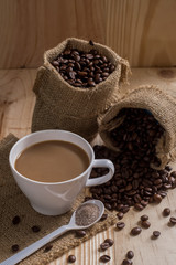Coffee cup and coffee beans in bag on wooden