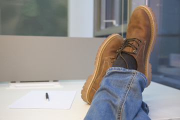 Man relaxing at the office with his feet on the table. - Powered by Adobe