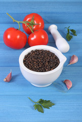 Black pepper in mortar and vegetables on blue boards