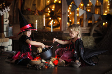 Fototapeta na wymiar Two little Halloween witches reading conjure above pot childh