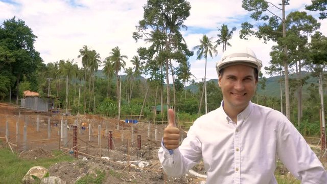 Portrait of smiling happy successfull engineer thumbs up at construction site