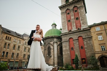 Obraz premium wedding couple walking on streets of city background old tower