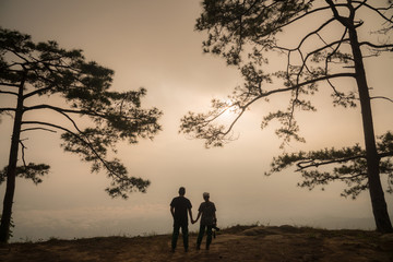 Fototapeta na wymiar The silhouette of Pine tree and couple on Phu Kradueng national park of Loei province of Thailand.