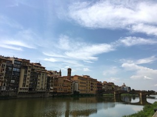 Fototapeta na wymiar FLORENCE, ITALY - JULY 25, 2016 : view of Florence riverbank with colorful traditional houses along the green river.