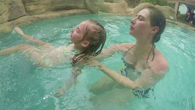 Mom teaches daughter to lie on your back on the water