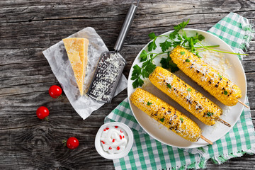 Grilled corn with cheese and parsley on white dish