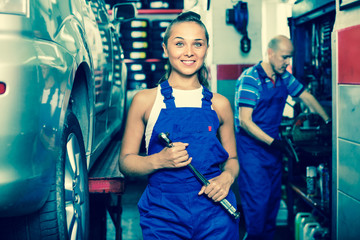 Woman in work coveralls working in auto service point