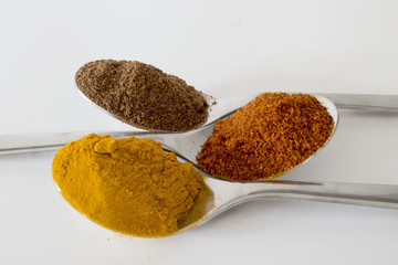 Spices in teaspoons on a white background