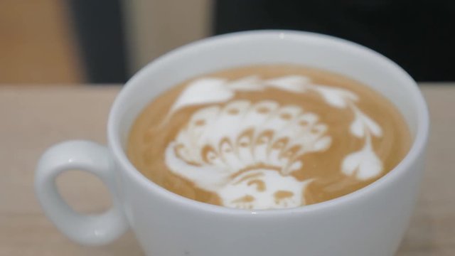 Close-up shot of barista creating cream picture of bird on latte matcha, making drops