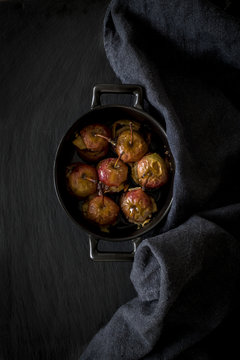 Roast apples in cocotte on slate background with kitchen towel.T