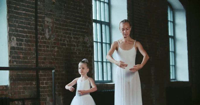 adult ballerina practicing with the little girl and trains her Russian classical ballet