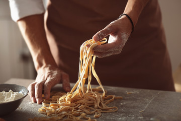 Man preparing pasta on kitchen table, close up view