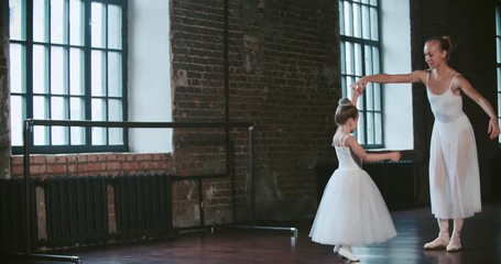 adult ballerina practicing with the little girl and trains her Russian classical ballet