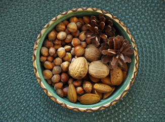 walnuts, hazelnuts and almonds in shells, one upon the other in ceramic bowl