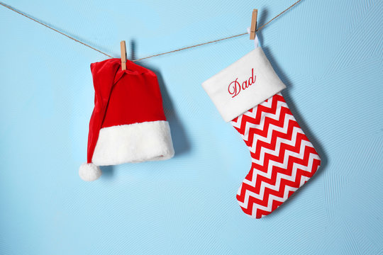 Christmas Stocking And Santa Claus Hat Hanging Against Blue Background