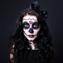 Halloween concept - close up of young woman with skull make up