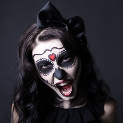 woman with creative Halloween skull make up screaming over black