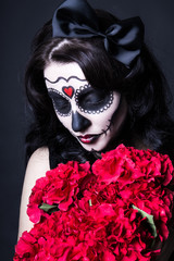 woman with creative Halloween skull make up and red flowers over