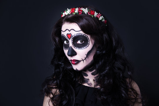 Halloween concept - close up of young woman with skull make up a