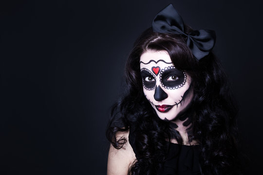 young smiling woman with Halloween skull make up over black and