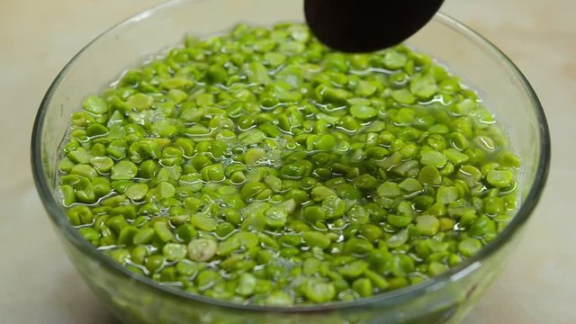 Green peas in the plate, part of them gaining to spoon