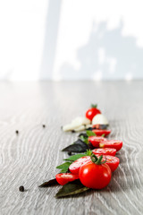 Cherry tomatoes, garlic and fresh basil on grey wooden  background. Frame. Copy space.