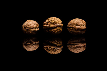 Three whole walnuts isolated on black background