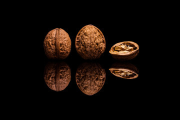 Two whole and one halved walnuts on black background
